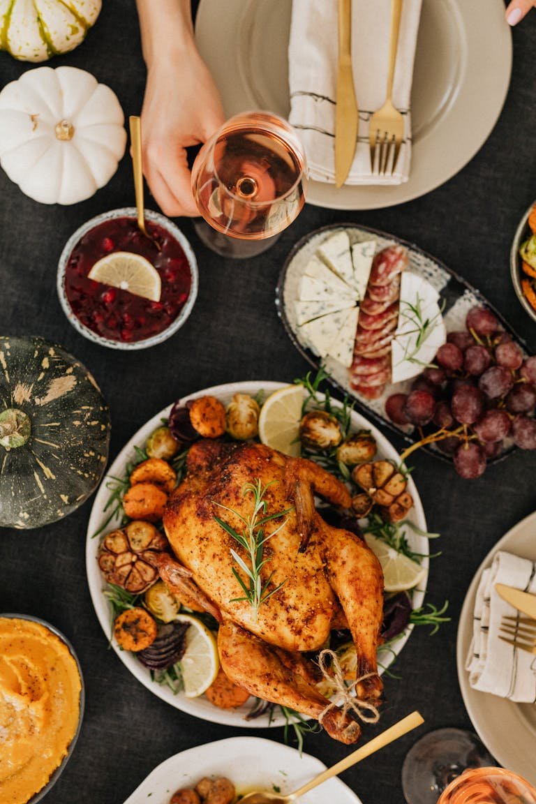 Top-down view of a Thanksgiving feast featuring roasted chicken, sides, and wine.