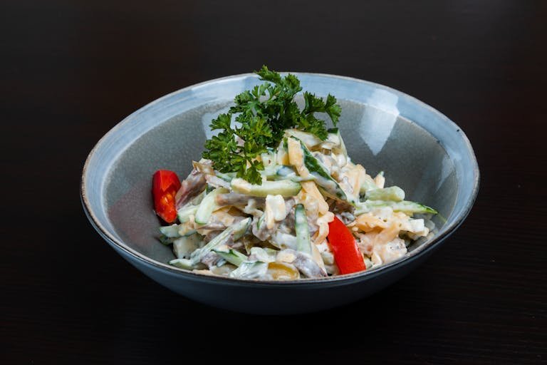 A fresh and colorful vegetable salad in a bowl with creamy dressing, perfect for healthy eating.