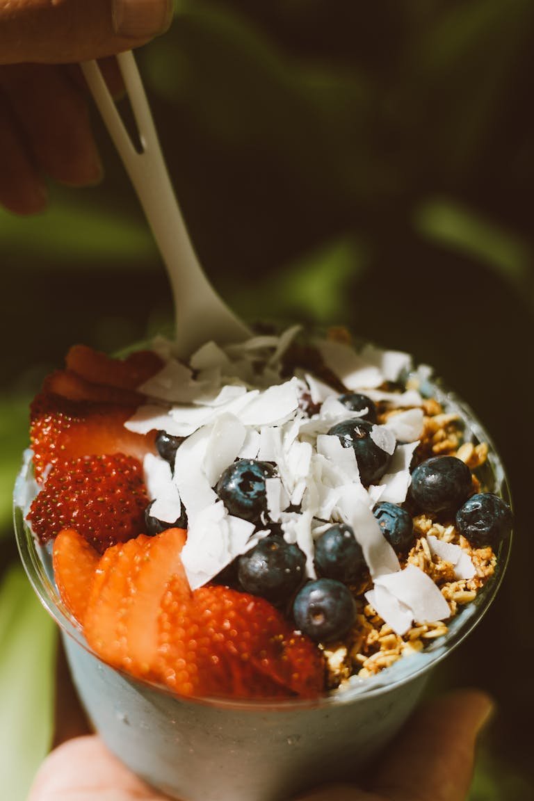 Delicious acai bowl topped with fresh strawberries, blueberries, and coconut flakes, perfect for a healthy snack.